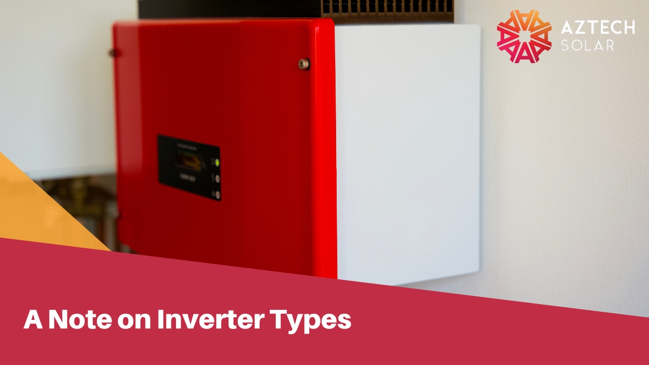A close-up of a red and white solar inverter mounted on a wall.