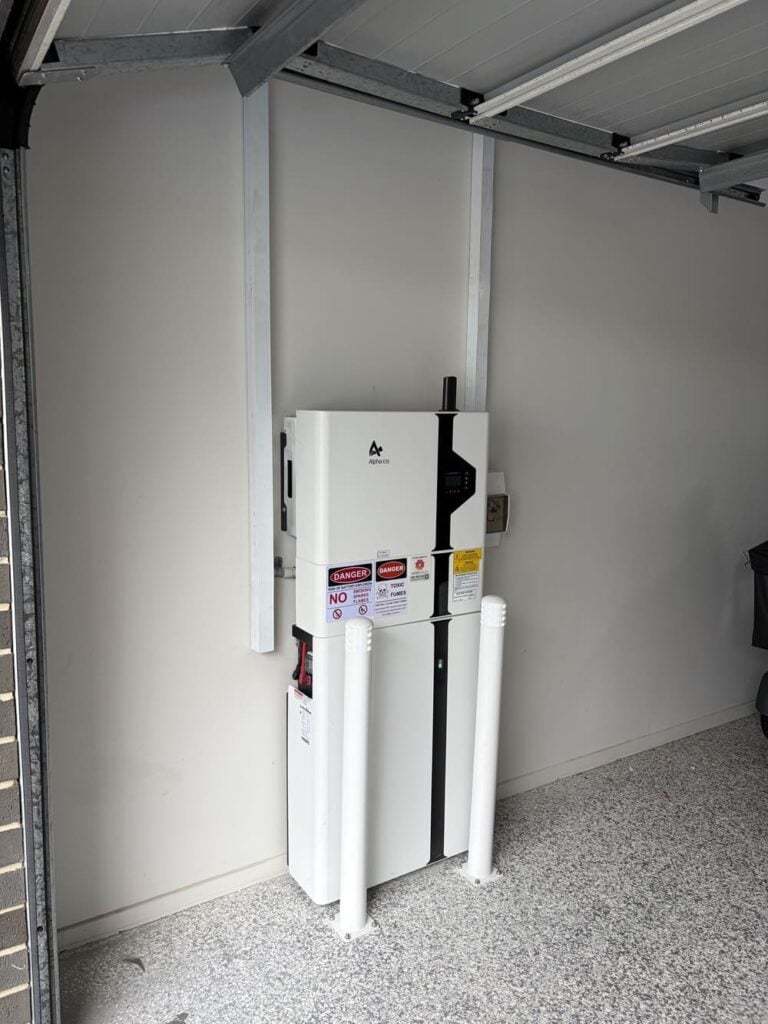 Wall-mounted home battery system in garage with bollards