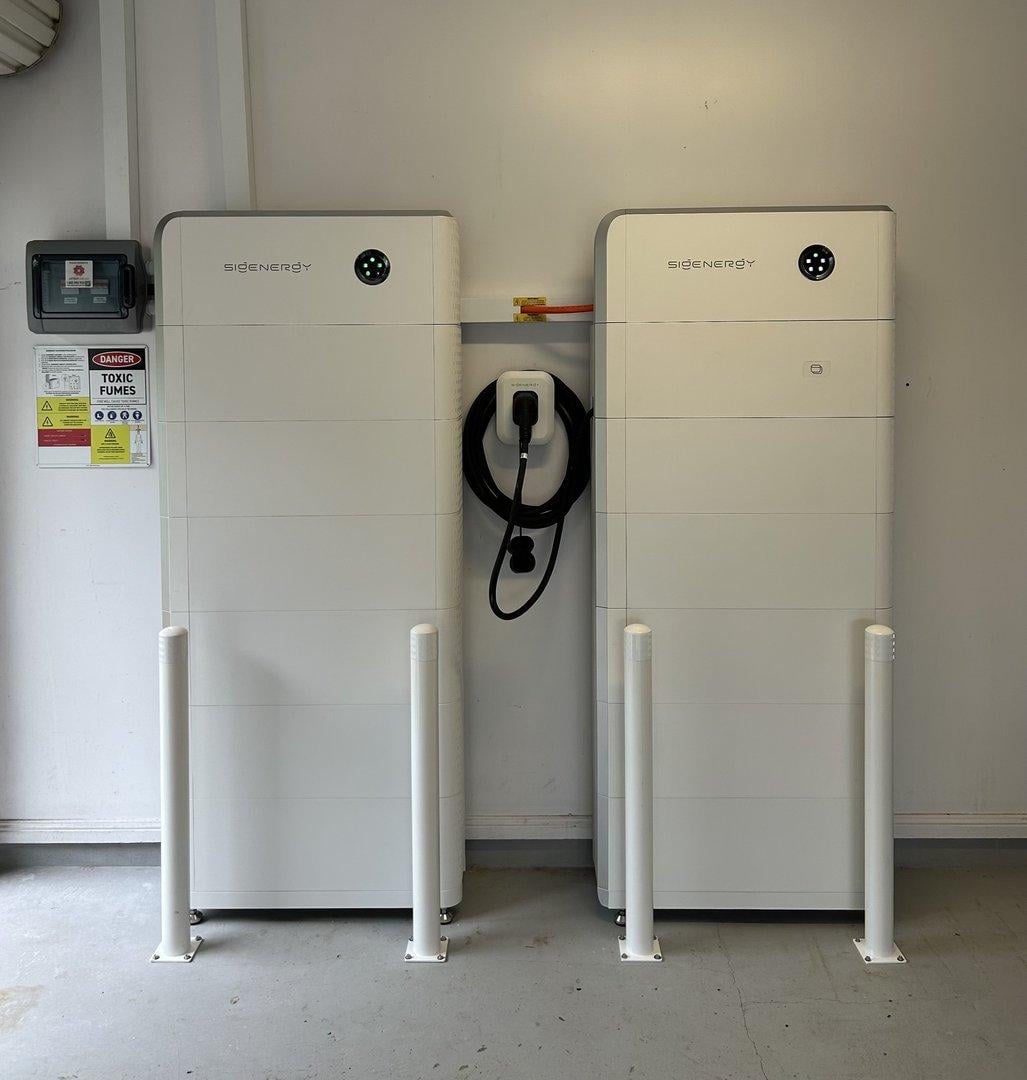 Two Sigenergy battery systems on a garage wall with an EV charger between them